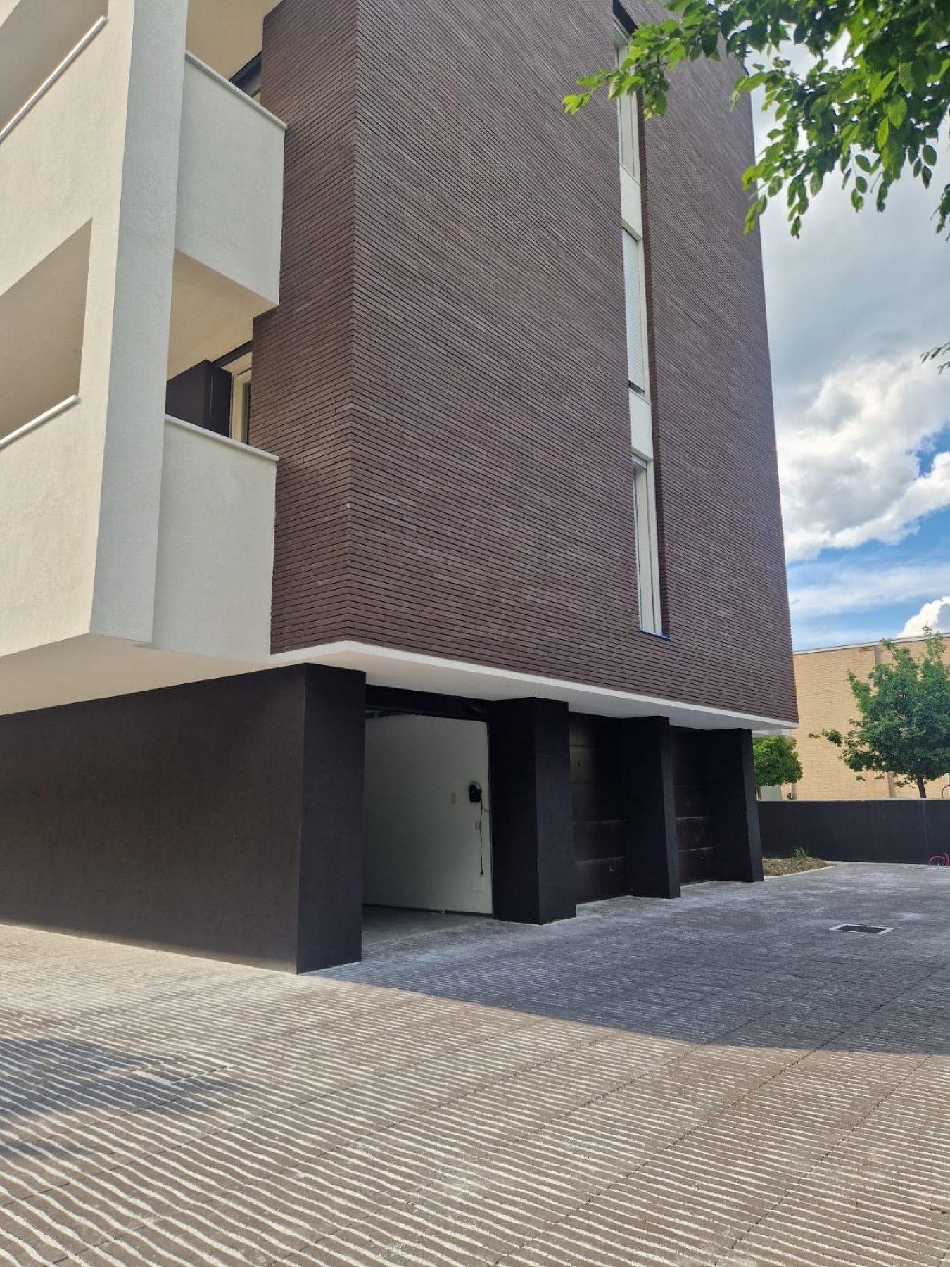 Edificio con rivestimento verticale in listelli scuri e area carrabile pavimentata